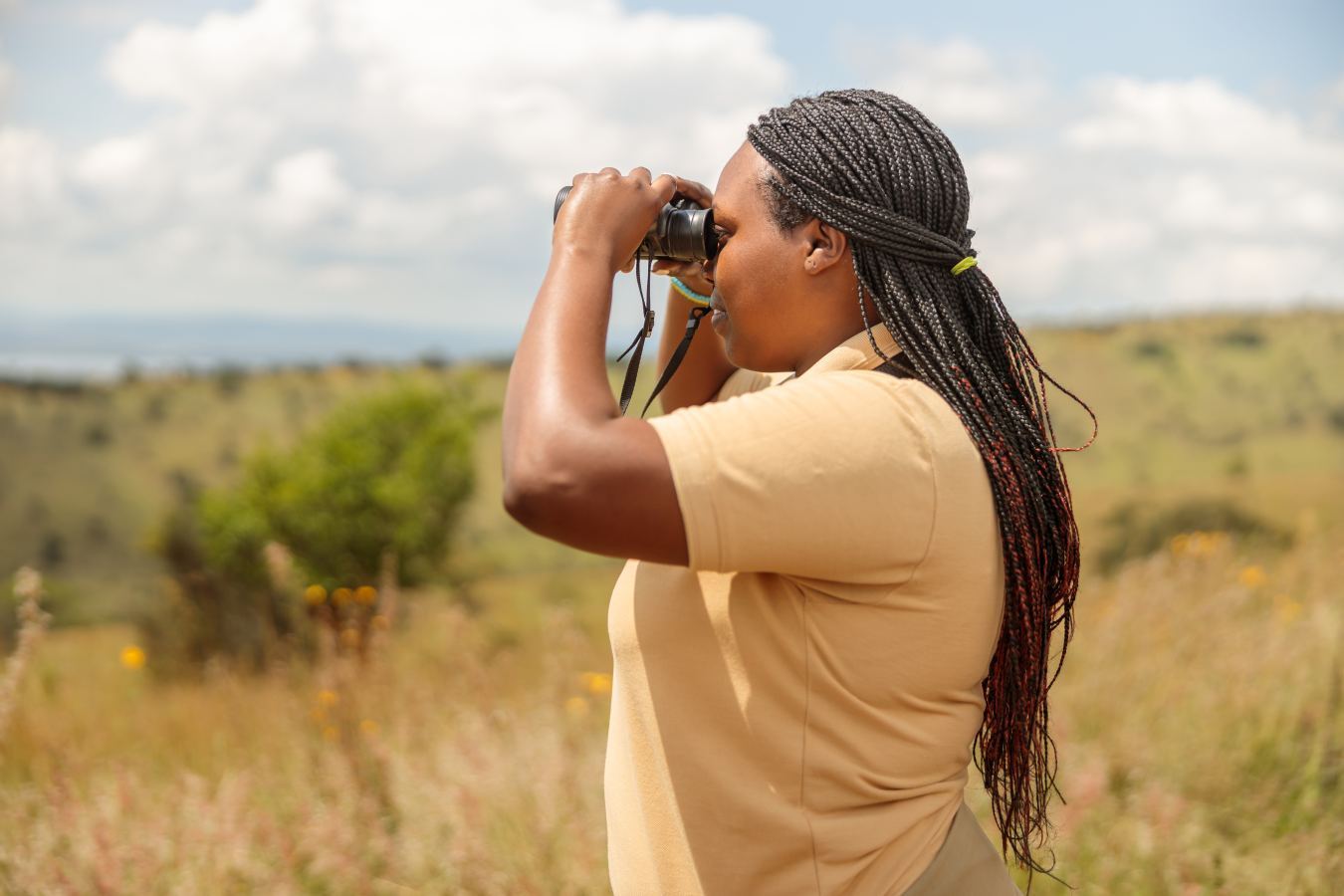 Guest using quality binoculars to spot wildlife from a safari vehicle