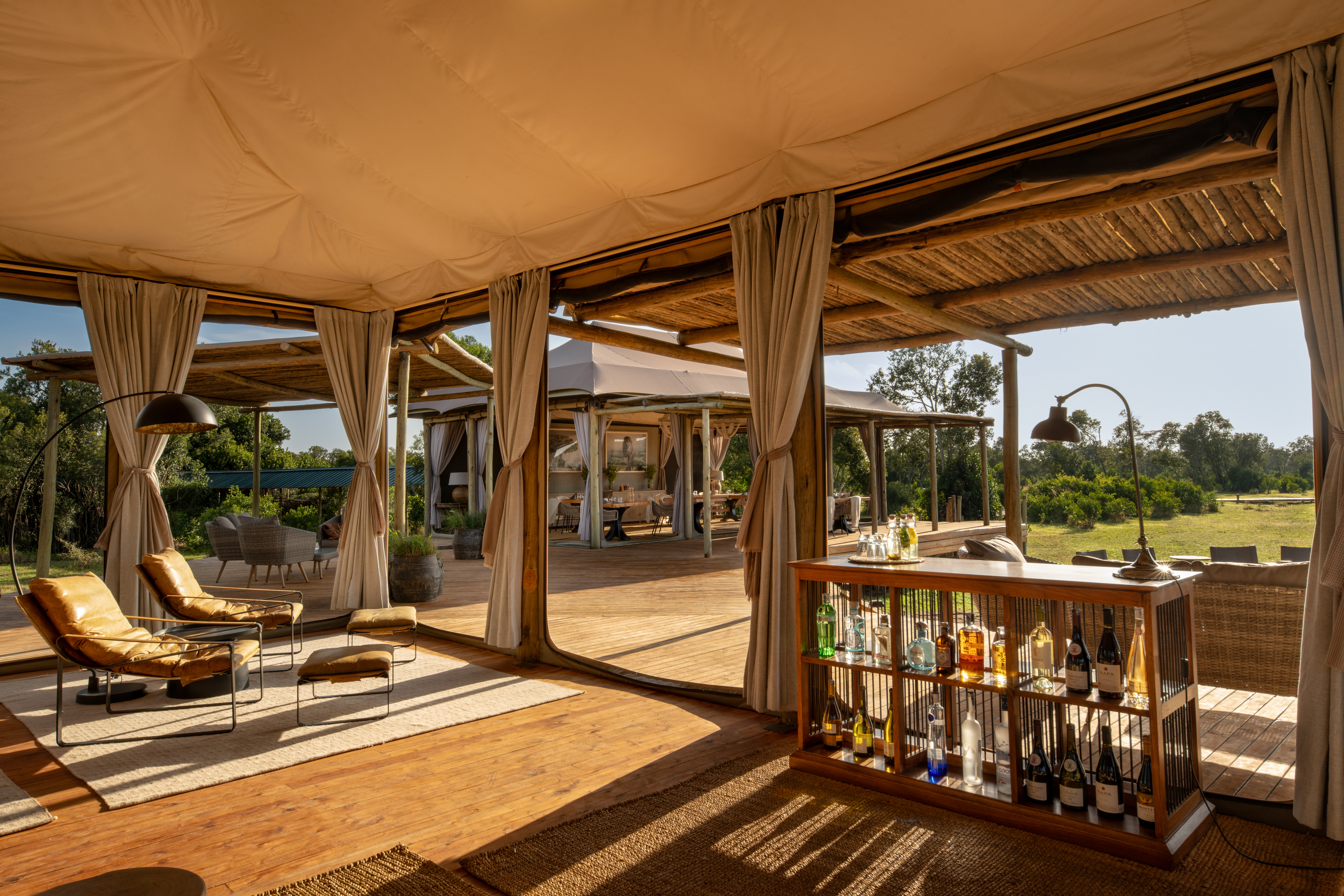 Luxury tented lodge at sunset with lanterns lit and the Serengeti plains behind