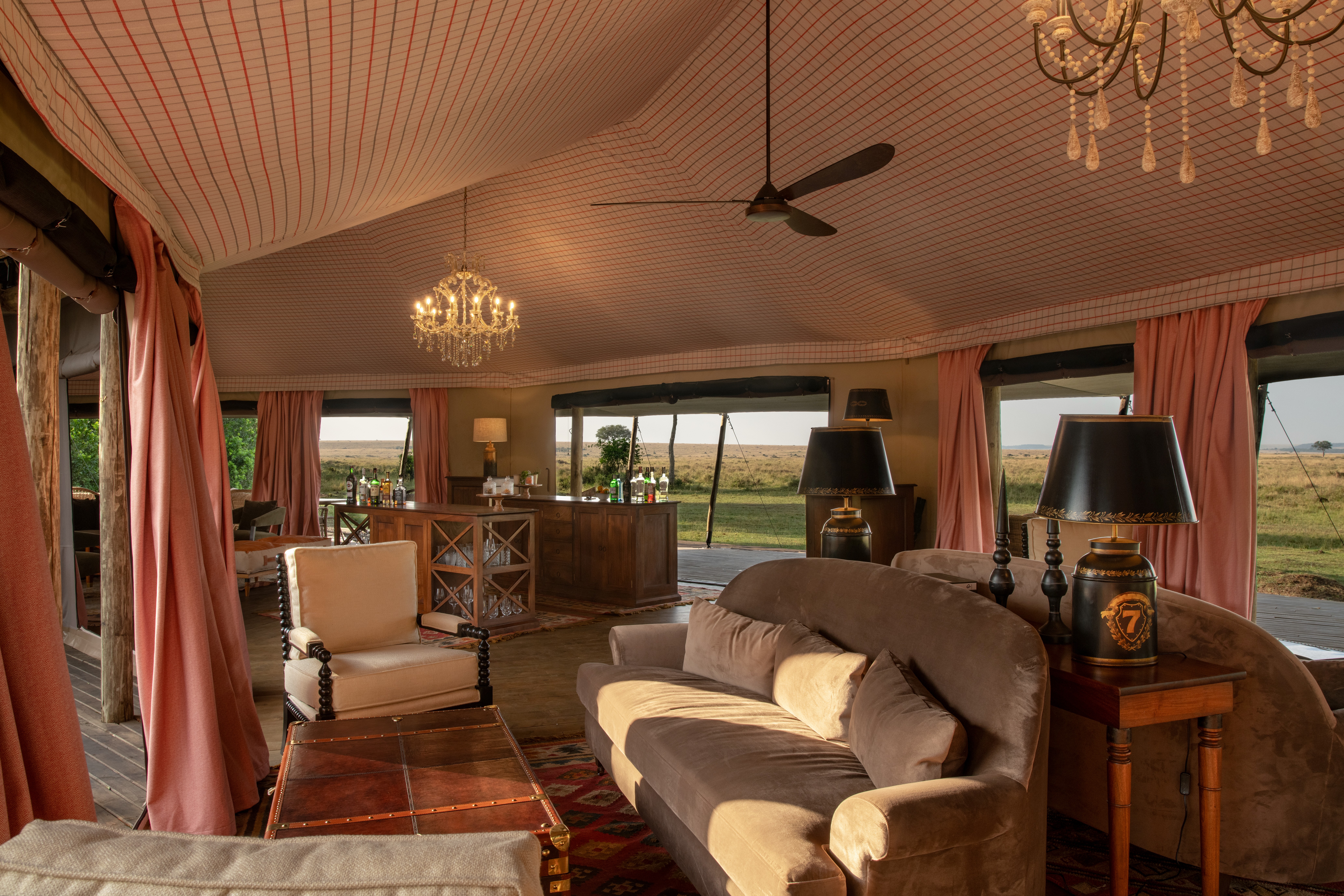 Interior of a luxury tented suite at a premier Serengeti safari camp with open canvas walls and bush views