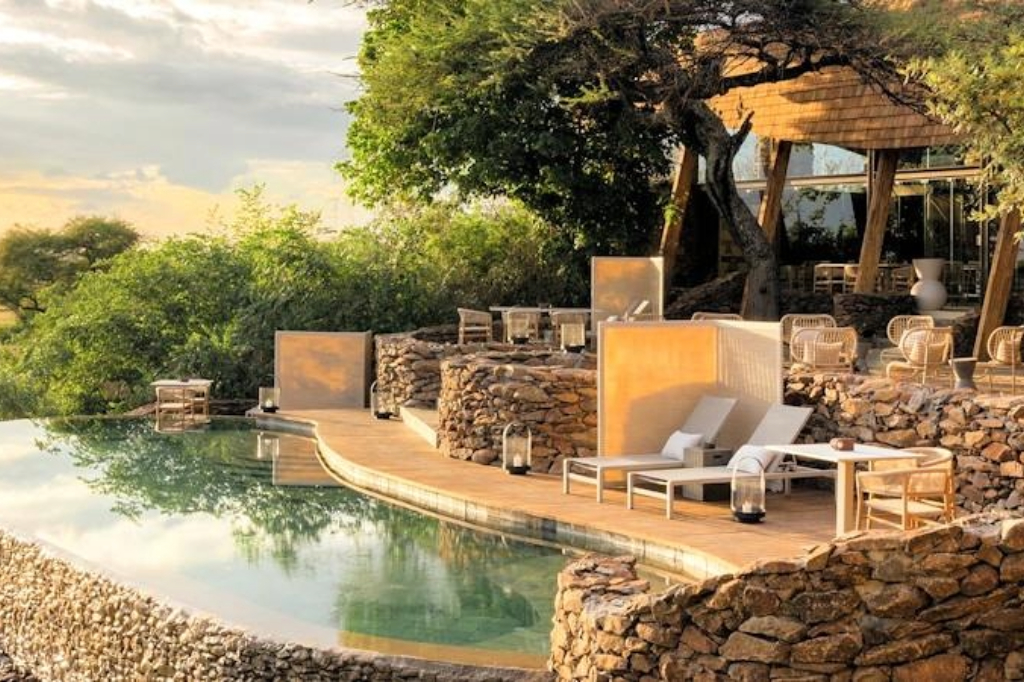 Off-road luxury safari vehicle tracking lions in Tanzania's Serengeti private concession at first light — the exclusive access that defines concession-based safari accommodation